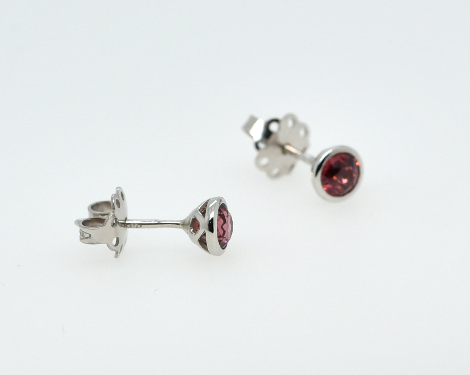 Balto aukso auskarai su turmalinais baltame fone iš šono