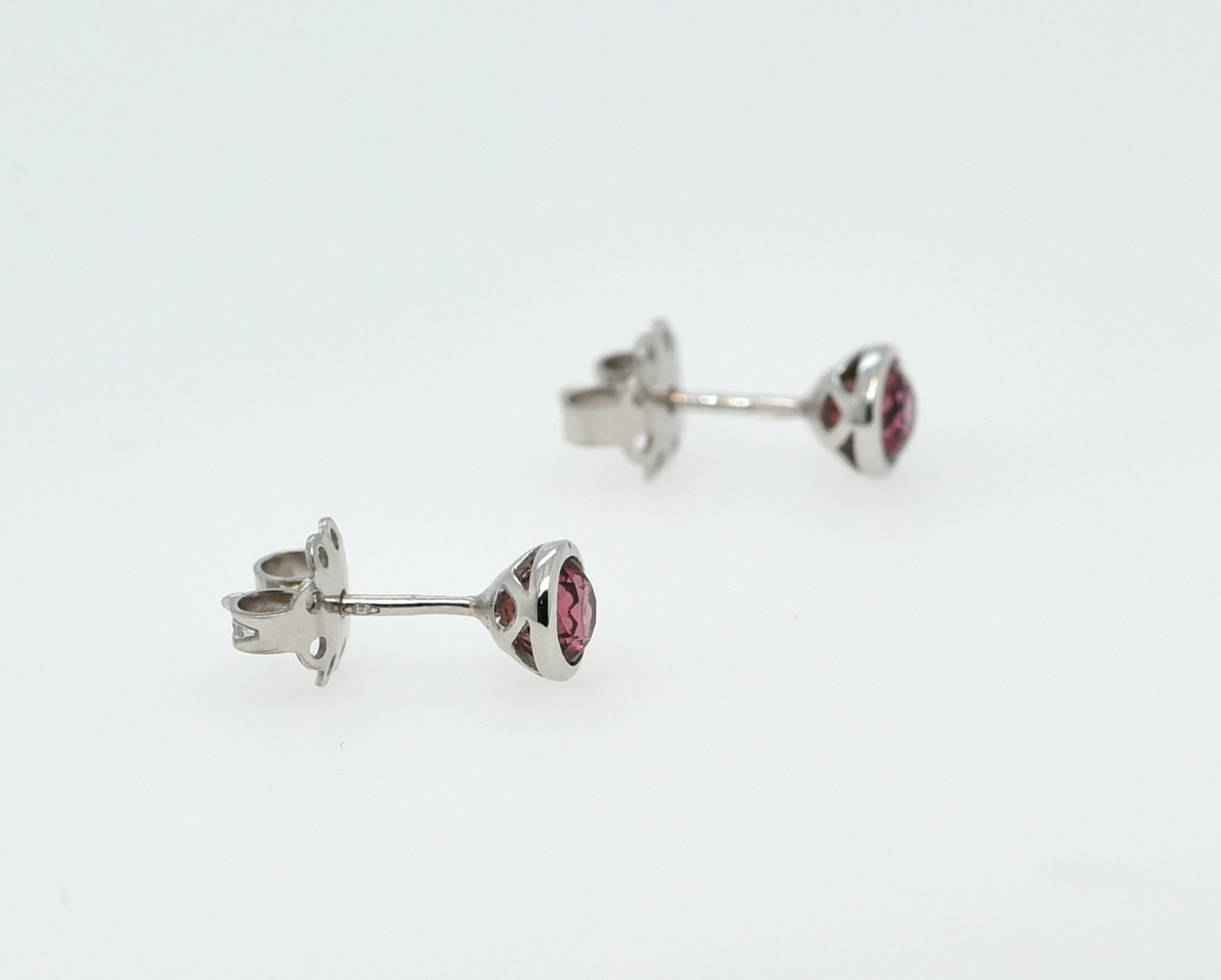 Balto aukso auskarai su turmalinais baltame fone iš šono