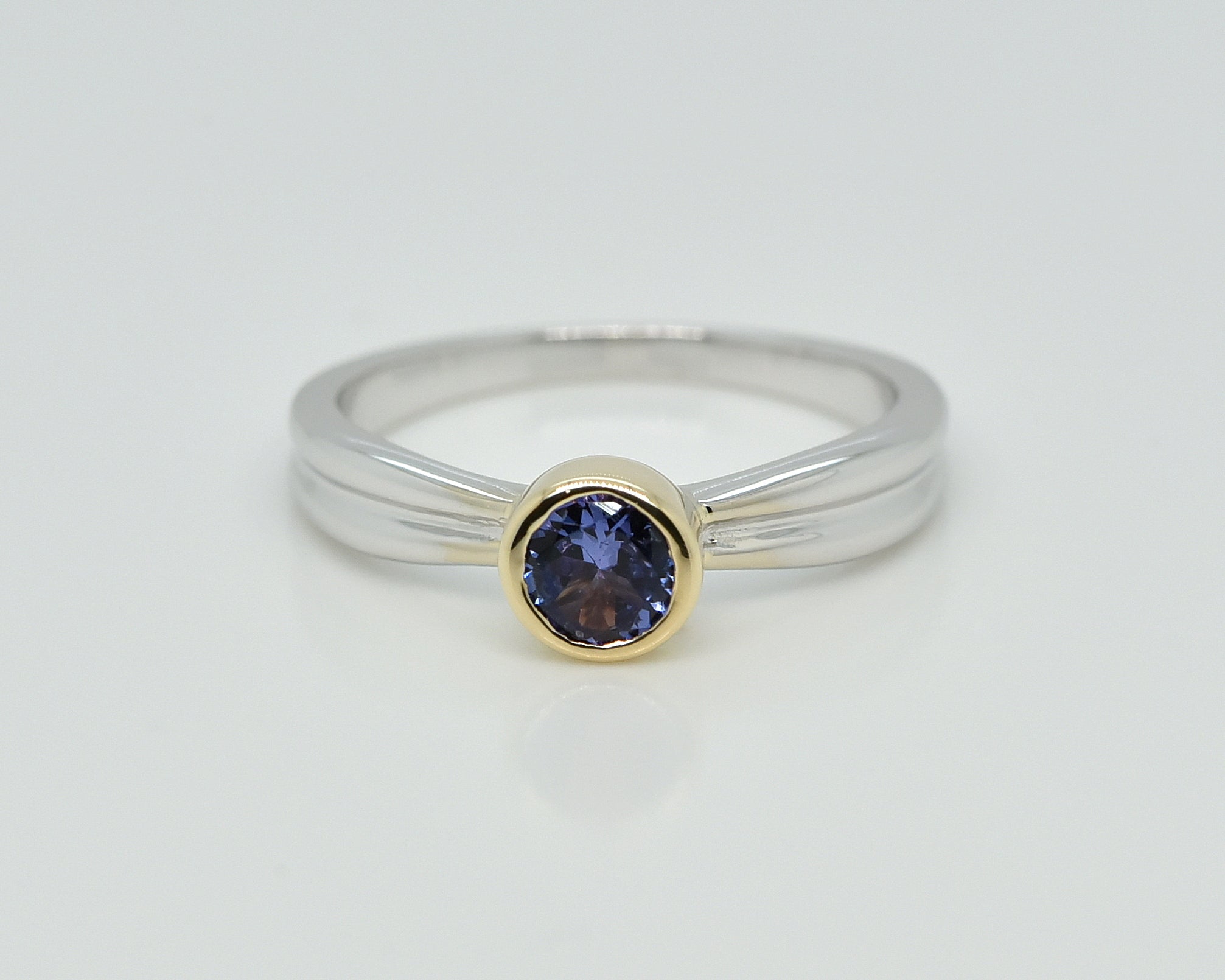 Balto aukso žiedas su tanzanitu baltame fone iš priekio